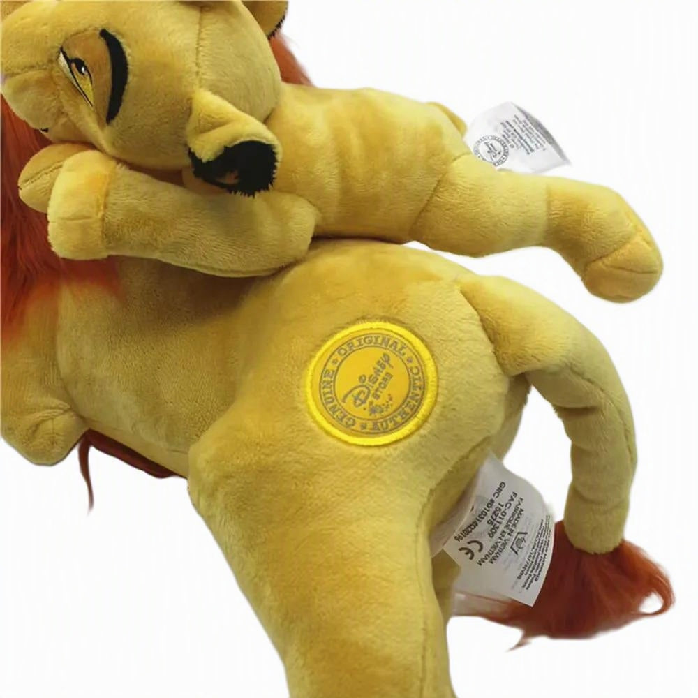 A plush lion toy photographed on a plain white background, showing its yellow body, orange-red mane and tail, embroidered facial features, and sewn-in tags. Official The Lion King Mufasa & Little Simba Premium Cotton Plush by Titantoons