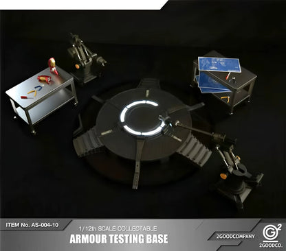 Model of an armour testing base with surrounding equipment on a dark background, featuring the 2GoodCompany logo. 2GOODCO 1/12 Scale LED Light Armor Testing Base Workshop Mechanical Diorama Set