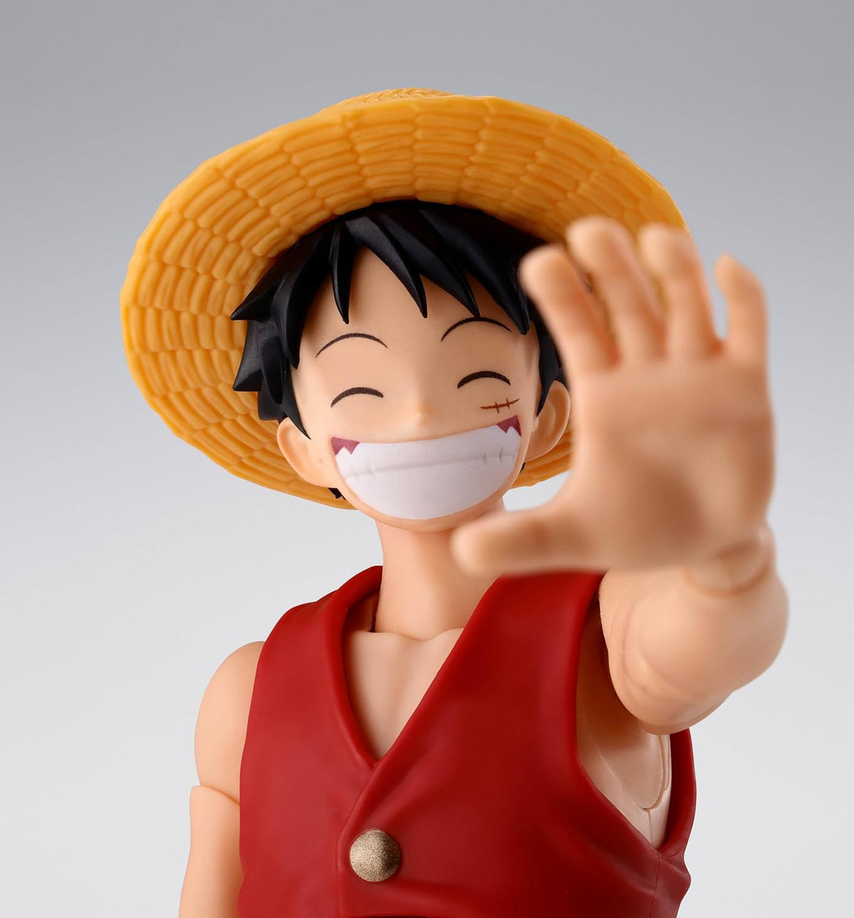 Figurine of a character with a straw hat and red vest, waving with one hand on a gray background One Piece: Shanks & Monkey D. Luffy (Childhood Ver.) Authentic S.H. Figuarts Fully Articulated Twin-Pack Action Figure Set by Bandai Spirits