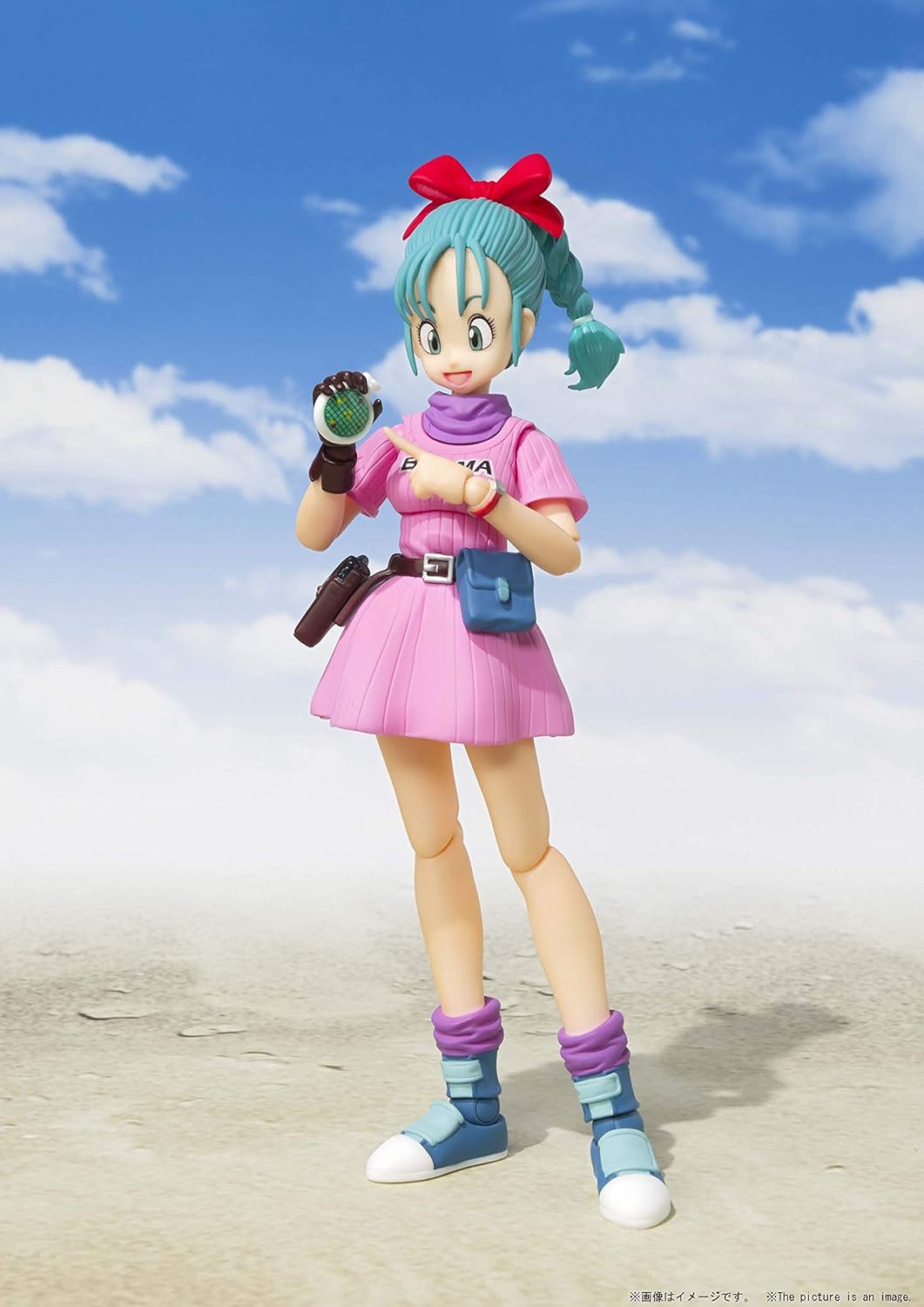 Action figure with green hair and a pink outfit standing on a beach with blue sky and clouds. Bandai S.H.Figuarts Dragon Ball: Bulma -Adventure Begins- Authentic Premium Action Figure