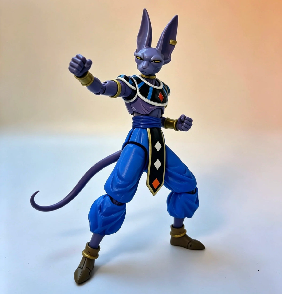 Action figure of a character with blue outfit and purple accents on a gradient background Bandai S.H.Figuarts Dragon Ball Super: God of Destruction Beerus Authentic Premium Action Figure