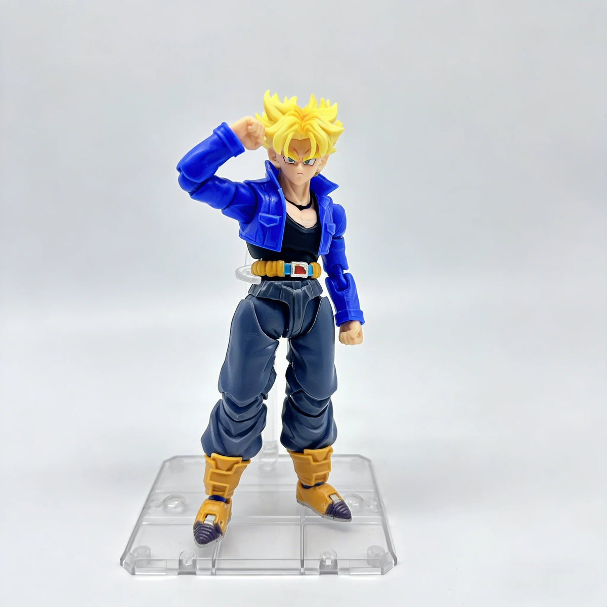 Action figure of a character in blue and yellow outfit on a clear stand with a white background Bandai S.H.Figuarts Dragon Ball Z: Super Saiyan Trunks Authentic Premium Action Figure
