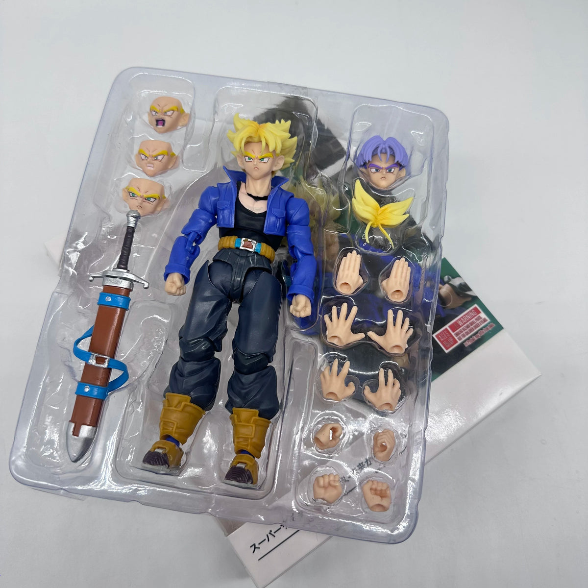 Action figure in packaging with interchangeable parts on a white background Bandai S.H.Figuarts Dragon Ball Z: Super Saiyan Trunks Authentic Premium Action Figure