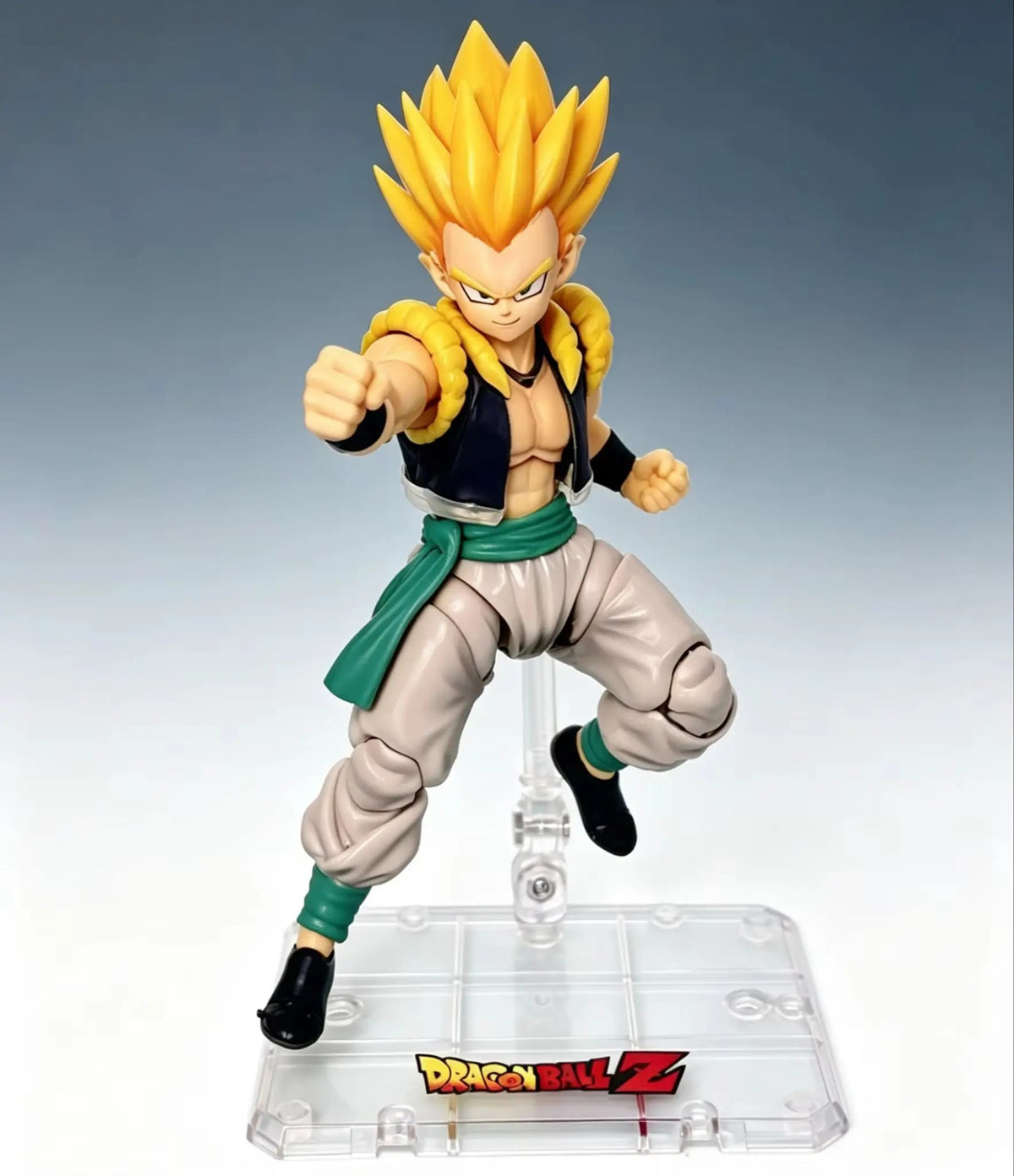 Action figure of a character from Dragon Ball Z on a gray background Bandai S.H.Figuarts Dragon Ball Z/Super: Super Saiyan Gotenks Authentic Premium Action Figure stand