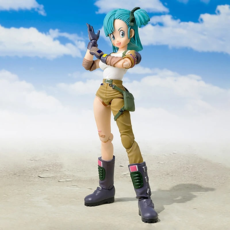 Action figure with blue hair and green outfit standing on a beach with blue sky and clouds. Bandai S.H.Figuarts Original Dragon Ball: Bulma Authentic Premium Action Figure
