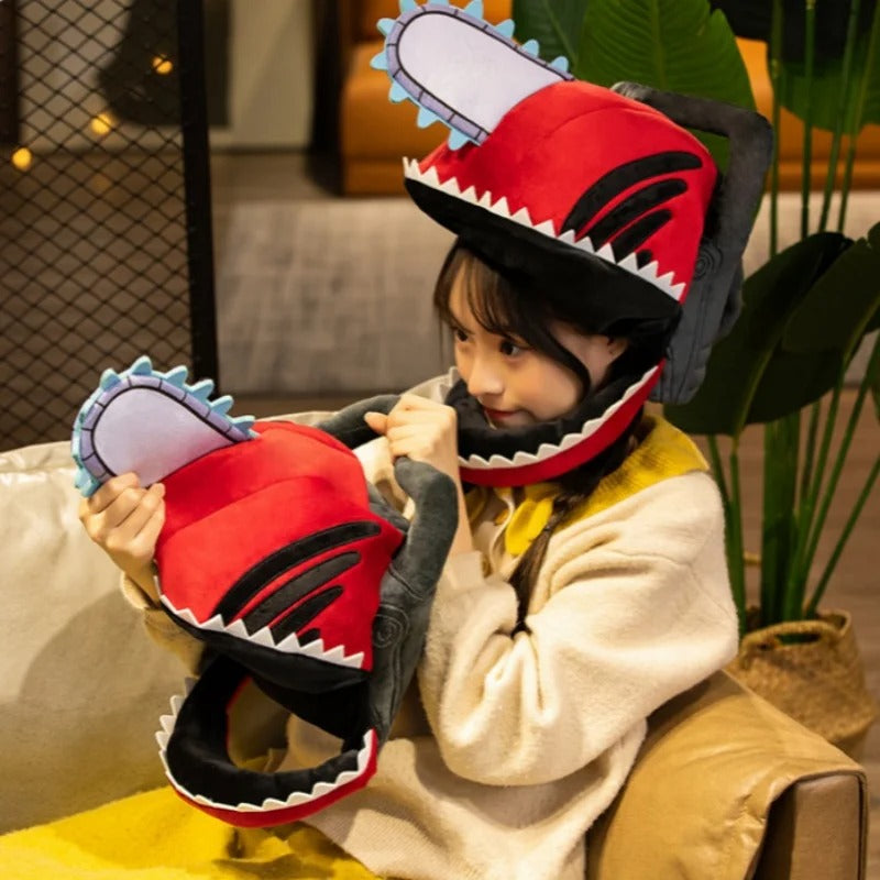 Child wearing a red and black shark-themed helmet with a chain saw design, sitting on a couch.  Chainsaw Man Denji Premium Plush Headgear Cosplay Helmet – 35x25cm Wearable Ultra-Soft Anime Costume Mask 