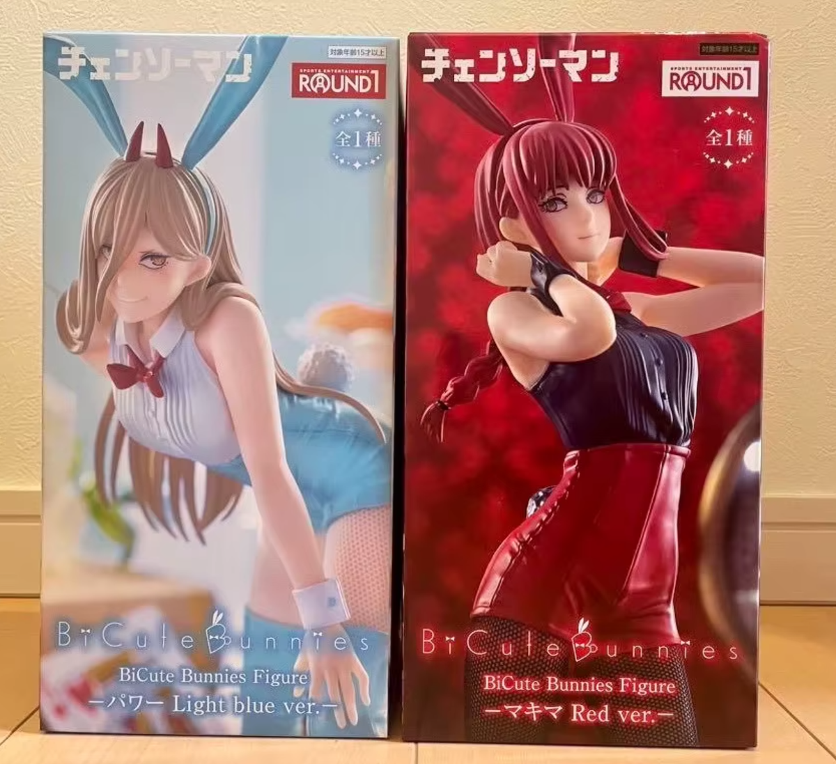 Two BtCute Bunnies figures in their packaging on a wooden floor. Chainsaw Man Power (Light Blue Ver.) & Makima (Red Ver.) Authentic BiCute Bunnies Figures – Real Fabric Fishnet Special Edition Individual Selection / Twin Pack Statue by FuRyu box