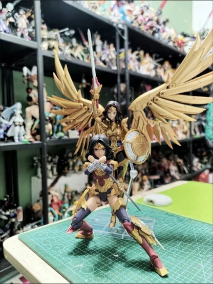 Two action figures with wings on a green cutting mat in a room filled with collectibles. DC Comics Wonder Woman (DC-01) 1/10 Scale Mecha-Girl Model Kit by MS General