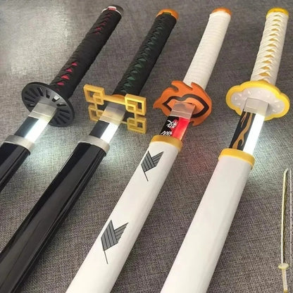 Four sword handles with different designs on a textured surface Demon Slayer 40-Inch Illuminated LED Bamboo Nichirin Katana Prop Replicas – Next-Gen USB-C Rechargeable Touch-Activated Cosplay & Display Series