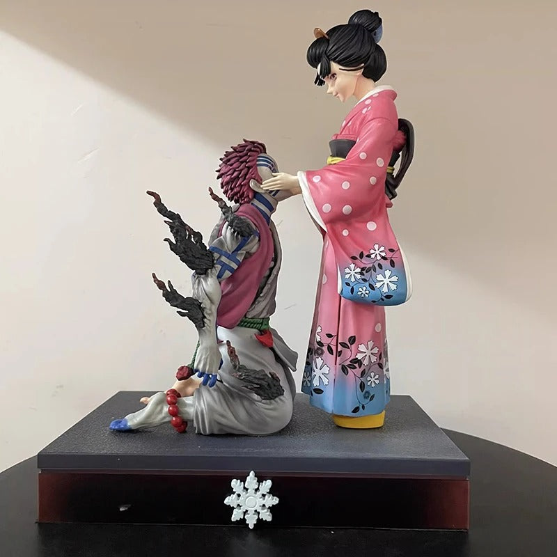Two figurines in traditional attire on a black base against a beige wall. Demon Slayer: Kimetsu no Yaiba Akaza (Hakuji) & Koyuki Authentic 10.43-Inch PVC Diorama Statue Figure – The Past Memories Edition 