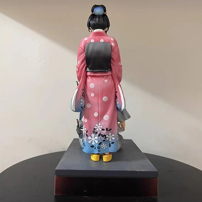 Statue of a person in traditional attire with a pink robe on a black base against a beige wall. Demon Slayer: Kimetsu no Yaiba Akaza (Hakuji) & Koyuki Authentic 10.43-Inch PVC Diorama Statue Figure – The Past Memories Edition