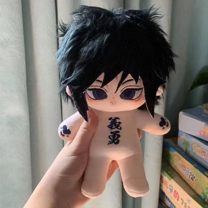 Plush toy with black hair and red eyes held by a hand, with books in the background. Demon Slayer: Kimetsu no Yaiba Giyu Tomioka Premium 20cm Super Soft Plushie Doll – Embroidered Cat Paw Edition
