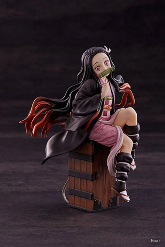 Figurine of a character with long black hair and red accents, sitting on a wooden crate against a dark background. Demon Slayer: Kimetsu no Yaiba Nezuko Kamado Authentic 15cm Sitting PVC Figure – Box Perch Display Edition