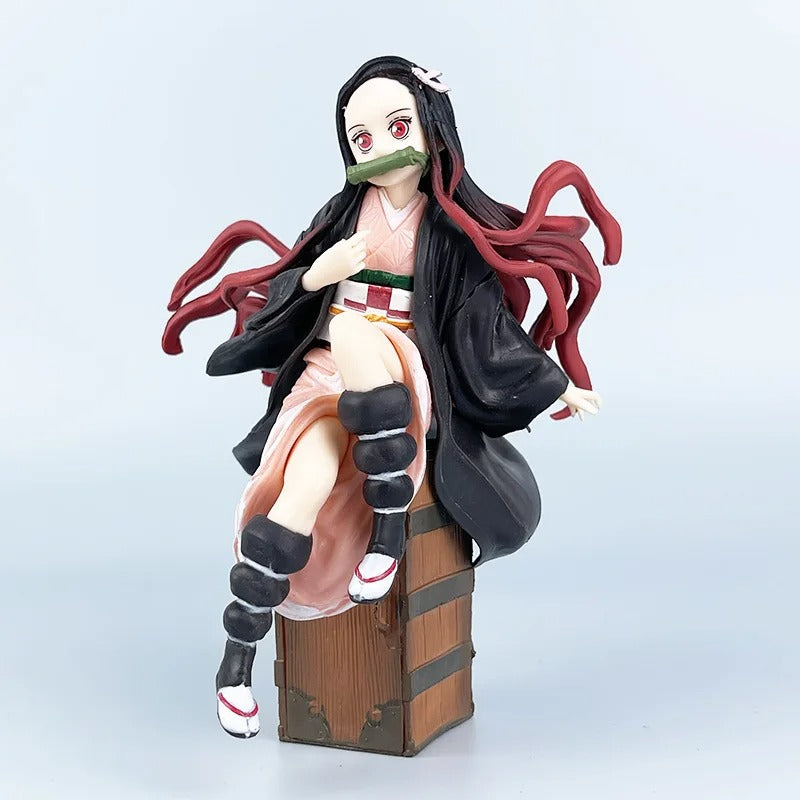Anime character figurine with long black and red hair, sitting on a wooden box against a light gray background.