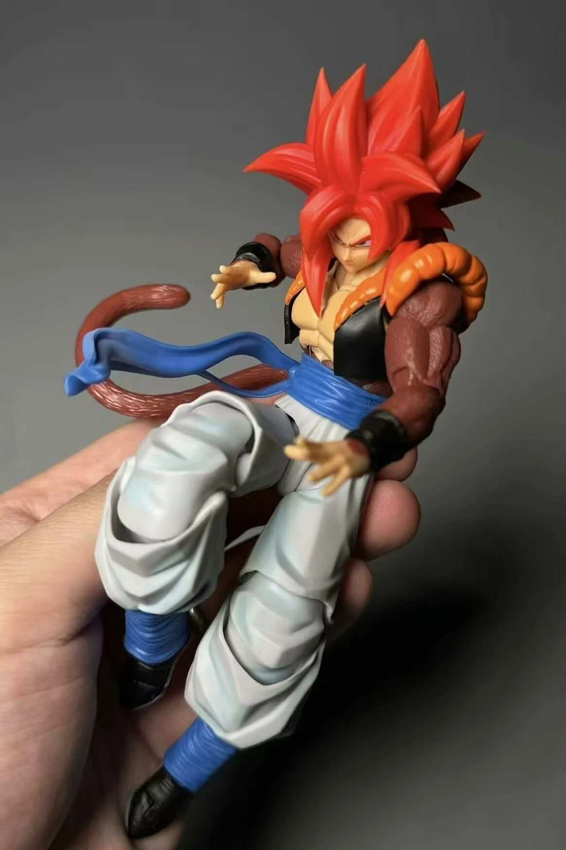 Action figure with red hair and blue accents held in a hand against a dark background Demoniacal Fit Dragon Ball GT/Z: Super Saiyan 4 Gogeta Authentic 15cm Premium 3.0 Generation Articulated Action Figure