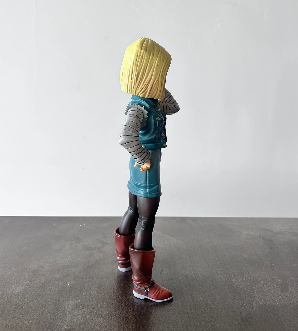 Toy figure of a character with blonde hair, blue outfit, and red boots standing on a dark surface with a white background. Dragon Ball Z: Android 18 (Lazuli) Premium 11-Inch Statue Figure – Android Saga Classic Denim Outfit Edition