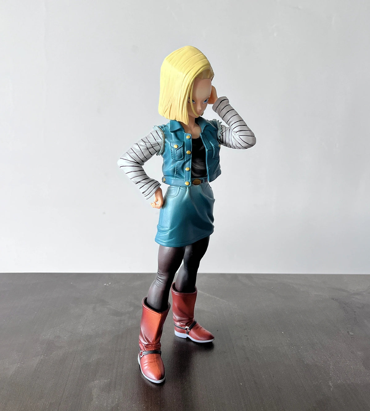 Action figure of a character with yellow hair, denim vest, and red boots on a gray background Dragon Ball Z: Android 18 (Lazuli) Premium 11-Inch Statue Figure – Android Saga Classic Denim Outfit Edition