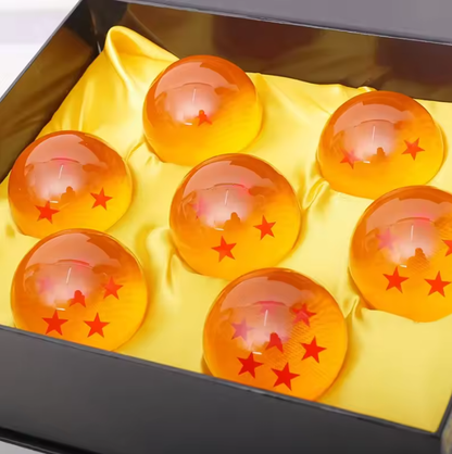 Set of orange balls with red star symbols on a yellow cloth inside a black box. Dragon Ball Z: Premium 2.2-Inch Crystal Star Ball – High-Density Resin Prop Replica & Desk Display Edition