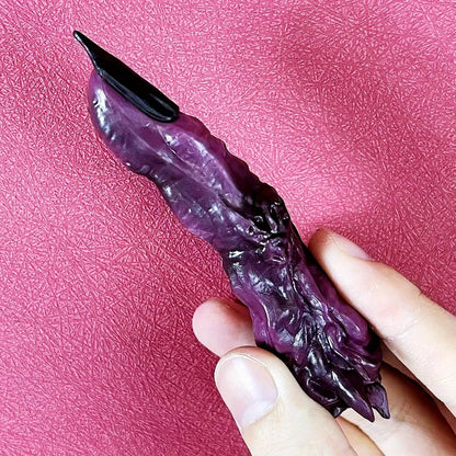 Purple and black object held in a hand against a pink textured background Jujutsu Kaisen Ryomen Sukuna Cursed Finger Authentic Figurine Prop Replica Set – Special Grade Cursed Object Edition with Talisman-Sealed Wooden Storage Box