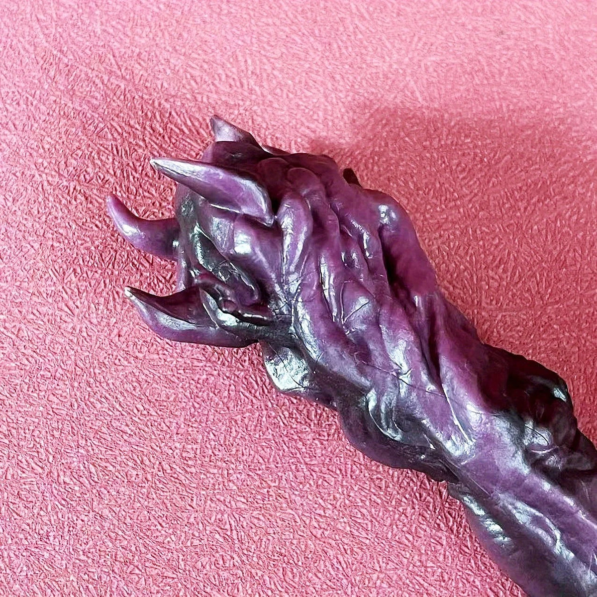 Purple claw-like object on a pink textured background Jujutsu Kaisen Ryomen Sukuna Cursed Finger Authentic Figurine Prop Replica Set – Special Grade Cursed Object Edition with Talisman-Sealed Wooden Storage Box finger