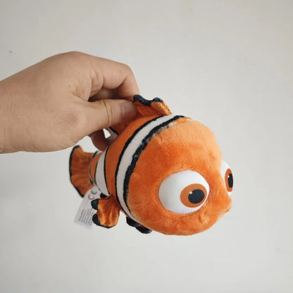 An orange and white clownfish plush toy being held by a person's hand against a plain light gray background. Official Finding Nemo & Dory Premium Best Friends Plush by Titantoons