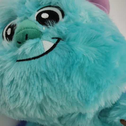Close-up of a fluffy turquoise blue monster plush toy with large black-and-white eyes, a green nose, and a stitched smile. Official Monsters University Sulley & Mike Premium Best Friends Plush Set by Titantoons ace