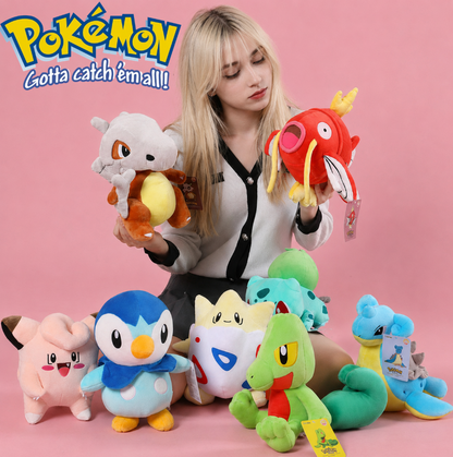 Woman holding various colorful plush toys with a pink background and 'Pokémon' branding. Official Pokémon Magikarp Premium Cotton Plush by Titantoons – 11.5-Inch