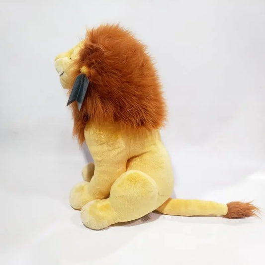 A plush lion toy shown from the side, sitting down, with a golden-yellow body and a fluffy orange-brown mane. It has a small dark gray tag attached to its neck and is photographed against a plain white background. Official The Lion King Adult Simba Premium Cotton Plush by Titantoons back