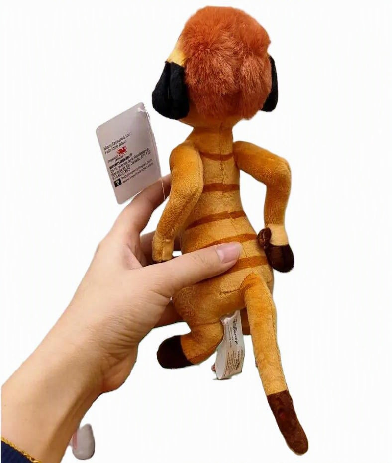 A small plush toy with an orange-brown furry head and body, black ear patches, and dark brown paws and tail tip, being held by a person's hand against a plain white background. Official The Lion King Timon Premium Cotton Plush by Titantoons back