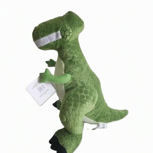 A green plush dinosaur toy with a textured scale pattern, white inner mouth, and black feet, shown against a plain white background with a product tag attached. 