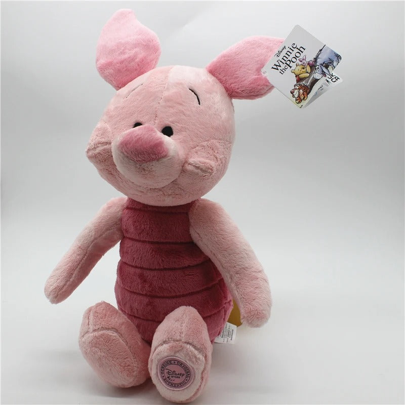 A pink plush toy of Winnie the Pooh, sitting and wearing a darker pink striped shirt, with a Disney tag attached to its ear, photographed on a light gray background. Official Winnie the Pooh & Friends Premium Cotton Plush Collection by Titantoons – Individual Storybook Characters or Complete 9-Piece Heirloom Nursery Set