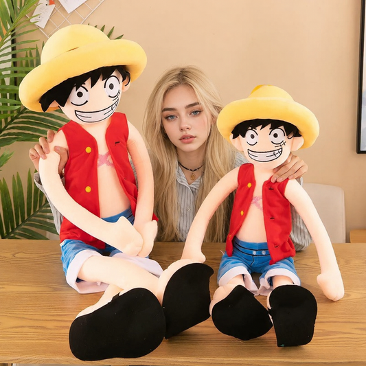 Two large plush toys resembling a character with a yellow hat and red vest, held by a person indoors. One Piece: Monkey D. Luffy Giant Luxury Anime Plush
