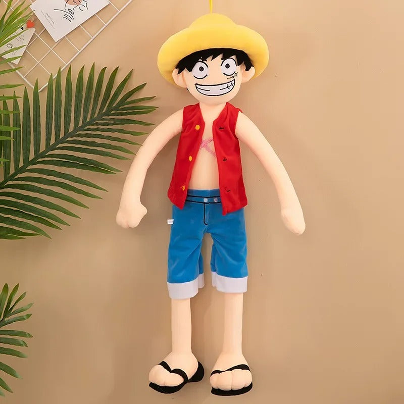 Plush toy of a character with a yellow hat, red vest, and blue shorts on a beige background. One Piece: Monkey D. Luffy Giant Luxury Anime Plush