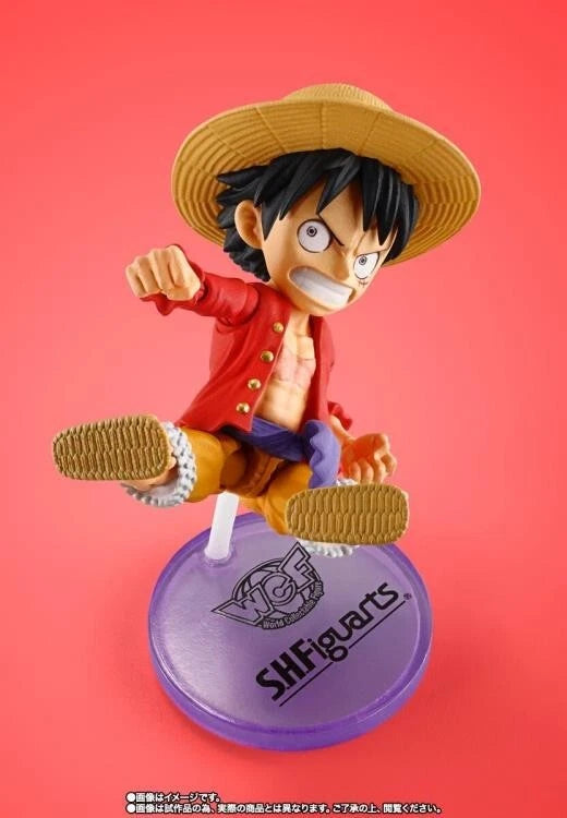 Figurine of a character from 'One Piece' on a red background with 'SHFiguarts' branding. One Piece: Monkey D. Luffy (WCF x S.H. Figuarts Ver.) Authentic Fully Articulated Chibi Action Figure by Bandai Spirits