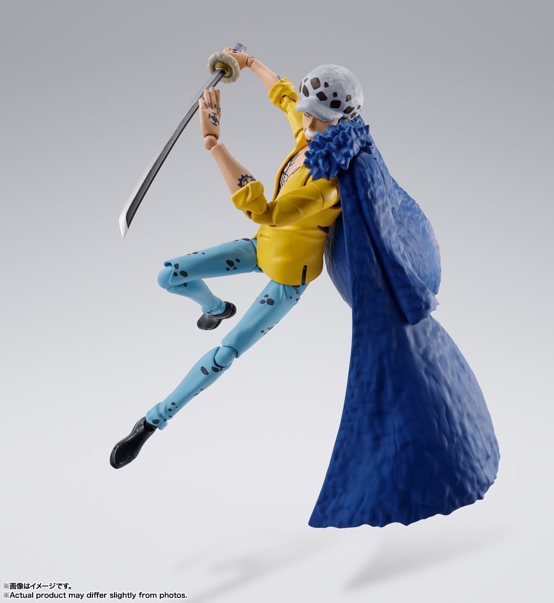 Action figure of a character in a yellow jacket and blue pants with a large blue fabric or cape, on a gray background. One Piece: Trafalgar Law (The Raid on Onigashima Ver.) Authentic S.H. Figuarts Fully Articulated Action Figure by Bandai Spirits