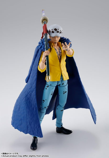 Action figure of a character with a blue cape and yellow shirt on a gray background One Piece: Trafalgar Law (The Raid on Onigashima Ver.) Authentic S.H. Figuarts Fully Articulated Action Figure by Bandai Spirits