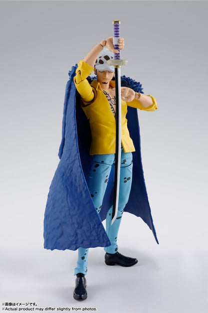 Action figure in a yellow jacket and blue pants holding a sword on a gray background One Piece: Trafalgar Law (The Raid on Onigashima Ver.) Authentic S.H. Figuarts Fully Articulated Action Figure by Bandai Spirits