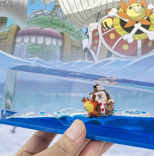Toy figure of a character in a ship on a transparent platform with a cartoonish background One Piece: Unsinkable Ship Liquid Drift Bottle – Thousand Sunny & Going Merry Premium Acrylic Desktop Motion Decor with Separate USB LED Illuminating Base