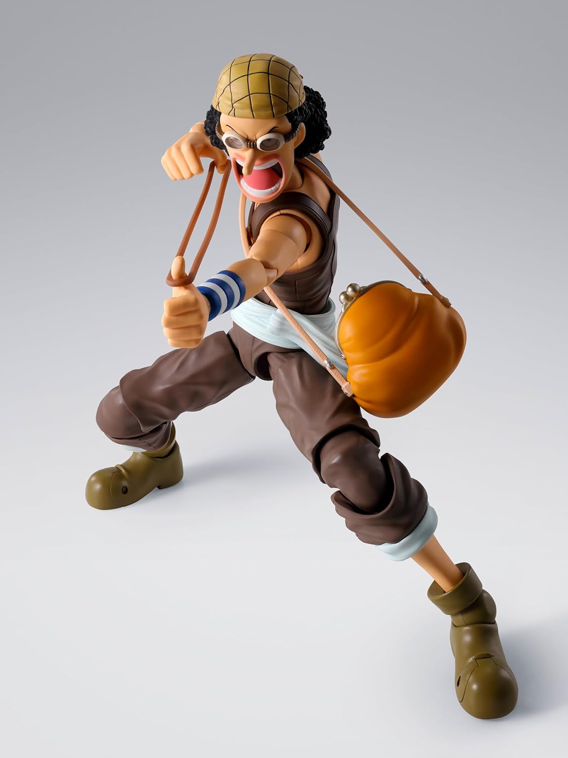 Action figure of a character from a popular anime series on a gray background One Piece: Usopp (Romance Dawn Ver.) Authentic S.H. Figuarts Fully Articulated Action Figure by Bandai Spirits