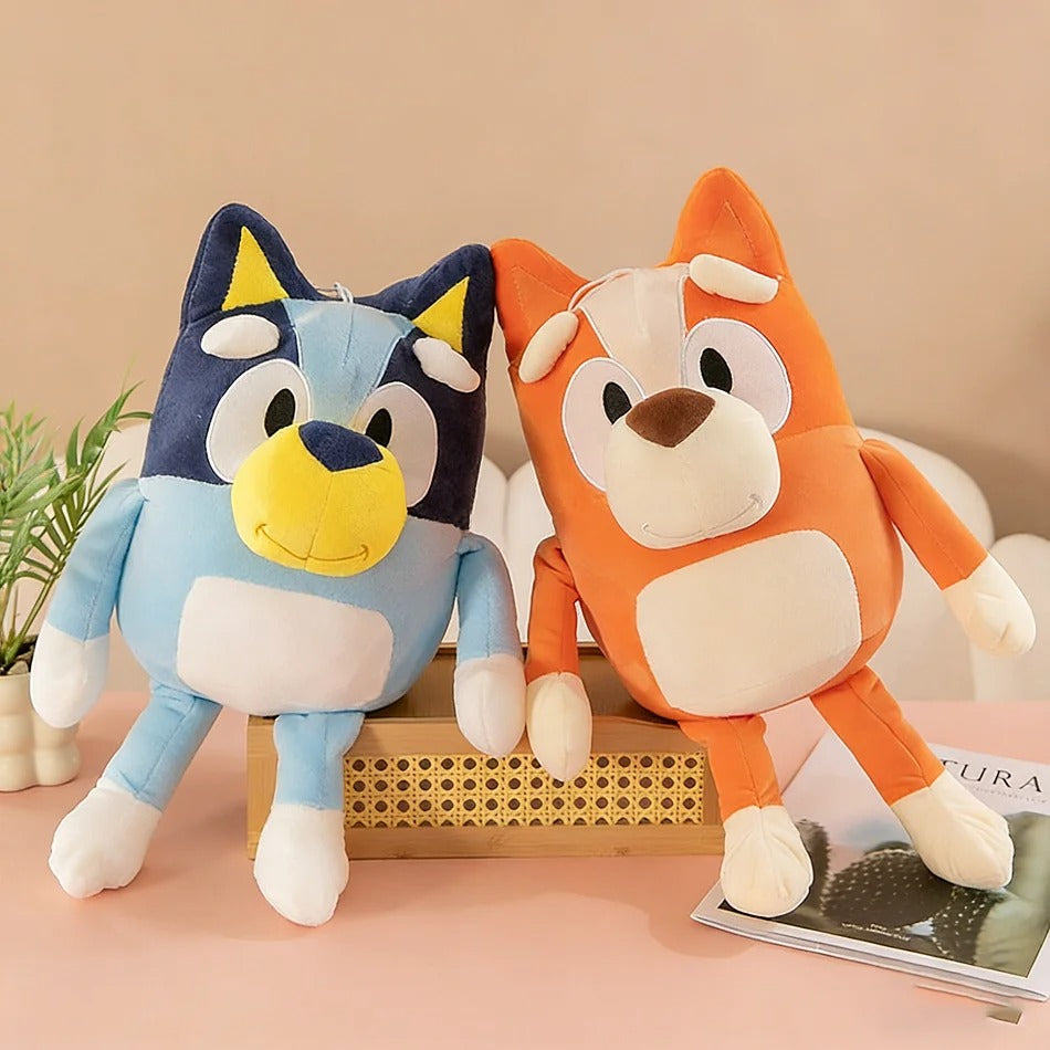 Two cartoon-style plush toys, one blue and one orange, on a beige surface with a plant in the background. Sweet Little Bingo Cuddle Friend – 14-Inch Premium Cotton Plush by Titantoons