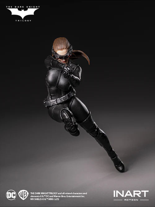 Action figure of a character in a black suit with a helmet, posed on a gray background, featuring logos for The Dark Knight Trilogy and INART Action.