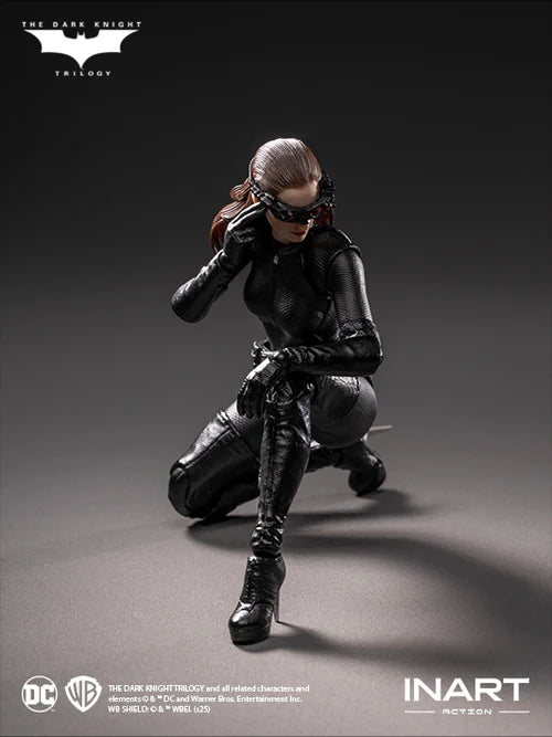 Action figure of a character in black costume with mask, kneeling on gray background, featuring 'The Dark Knight Trilogy' logo.