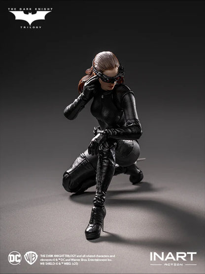 Action figure of a character in black costume with mask, kneeling on gray background, featuring 'The Dark Knight Trilogy' logo.