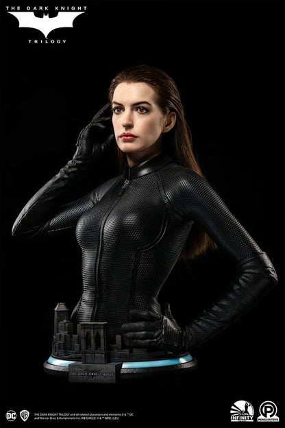 Statue of a character in a black suit with a dark background, featuring logos. The Dark Knight Rises Catwoman (Selina Kyle) 1:1 Scale Life-Size Masterpiece Bust by Infinity Studio x Penguin Toys